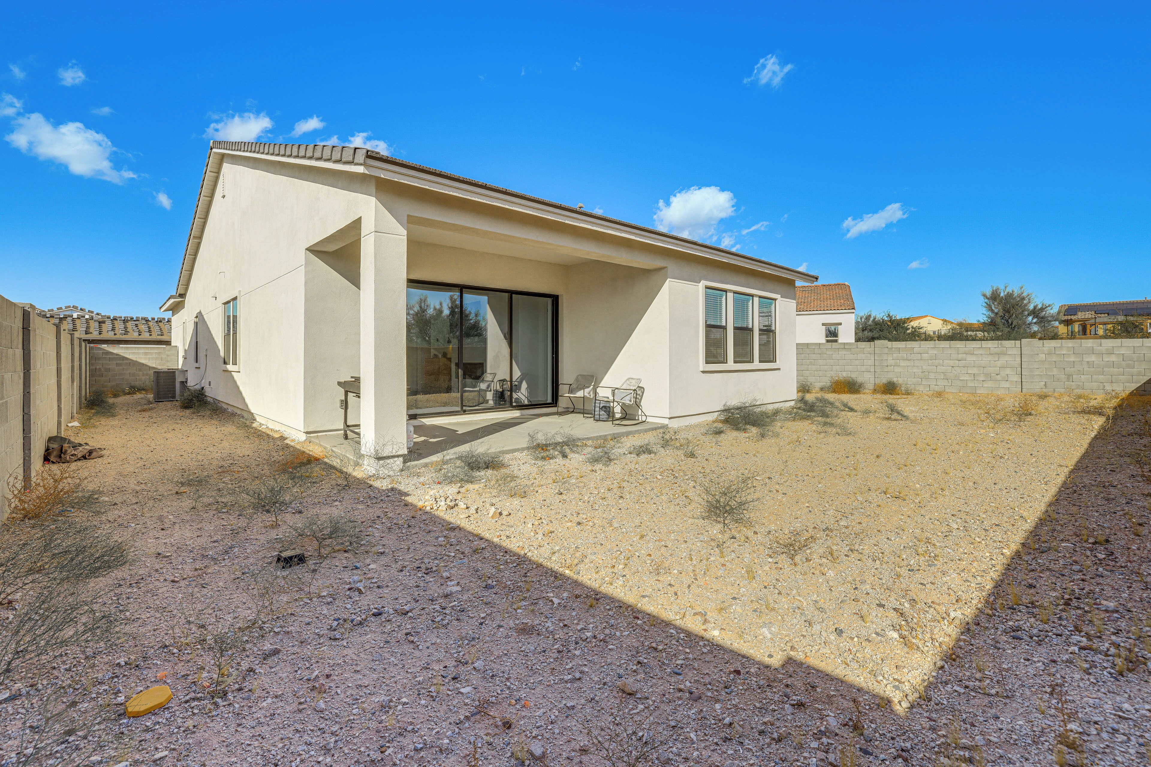 A modern house with a patio, large windows, and a gravel driveway.