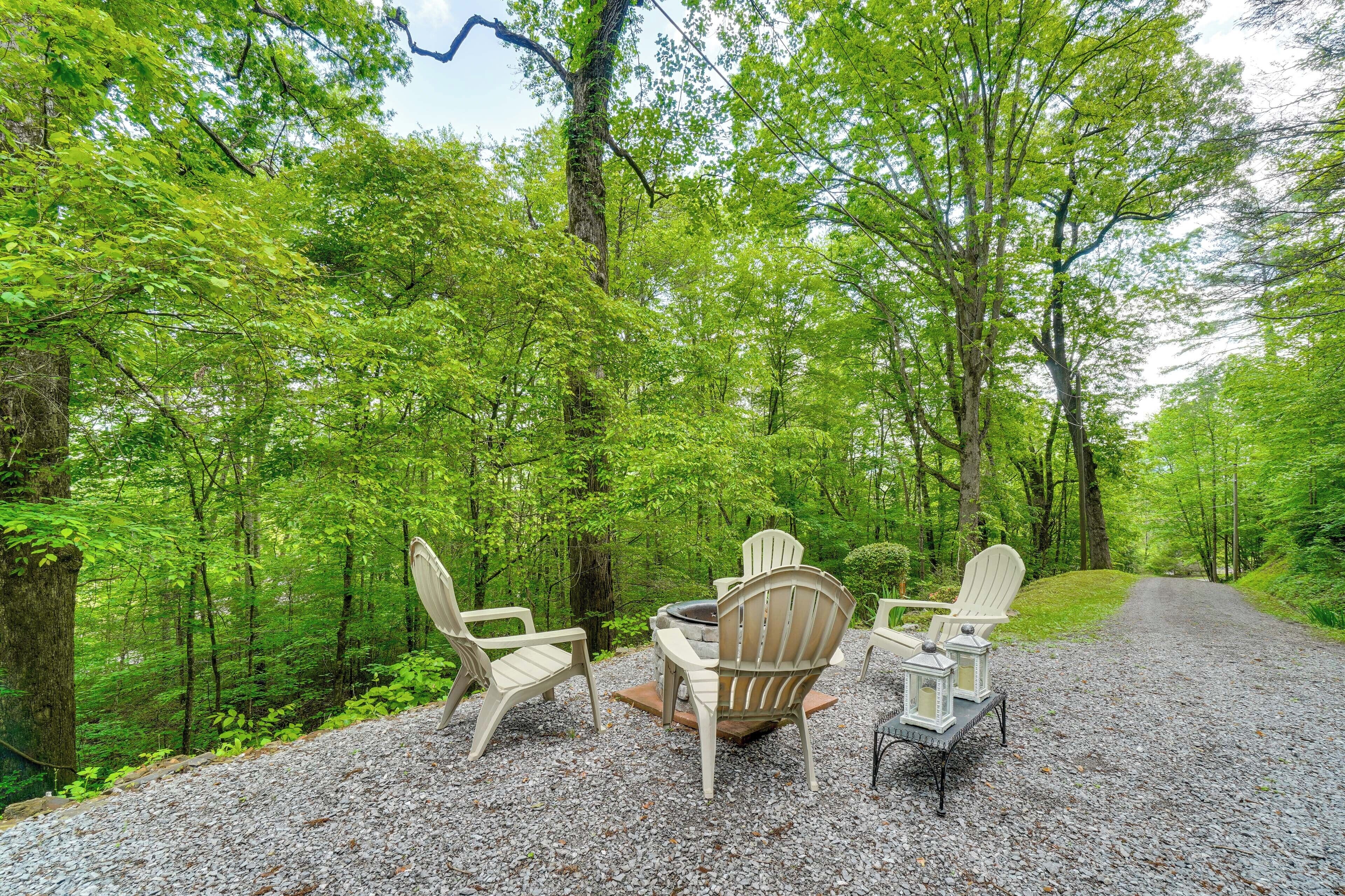 A gravel path leading through a forest with a table and chairs set up for outdoor dining.