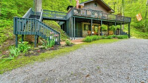A cabin with a covered porch, a staircase, and an American flag. - 'bear Acres Getaway' Cabin w/ Deck in Townsend! (Townsend)