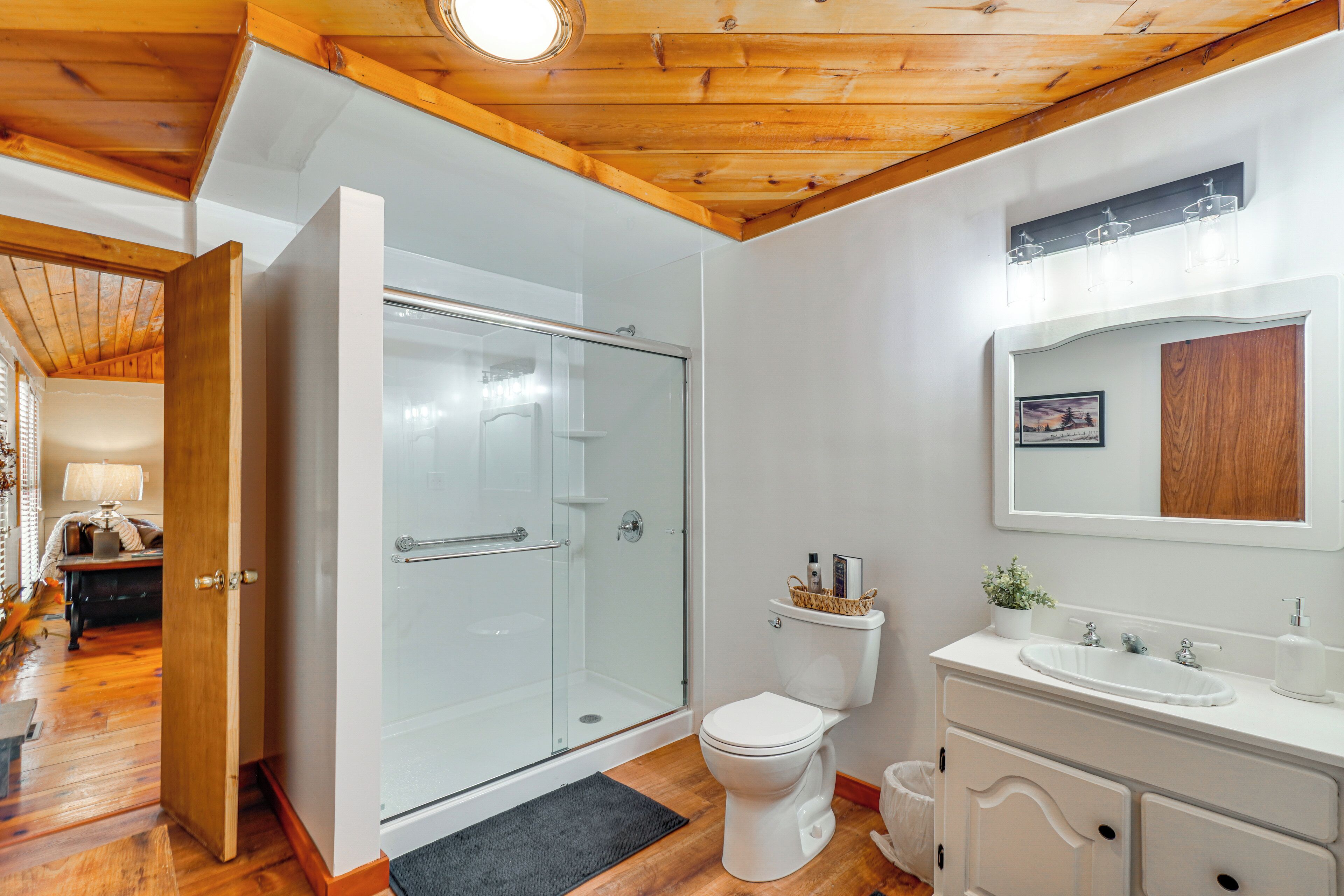 Une salle de bain moderne avec une douche à parois de verre, des toilettes blanches et un meuble-lavabo avec un évier et un miroir.