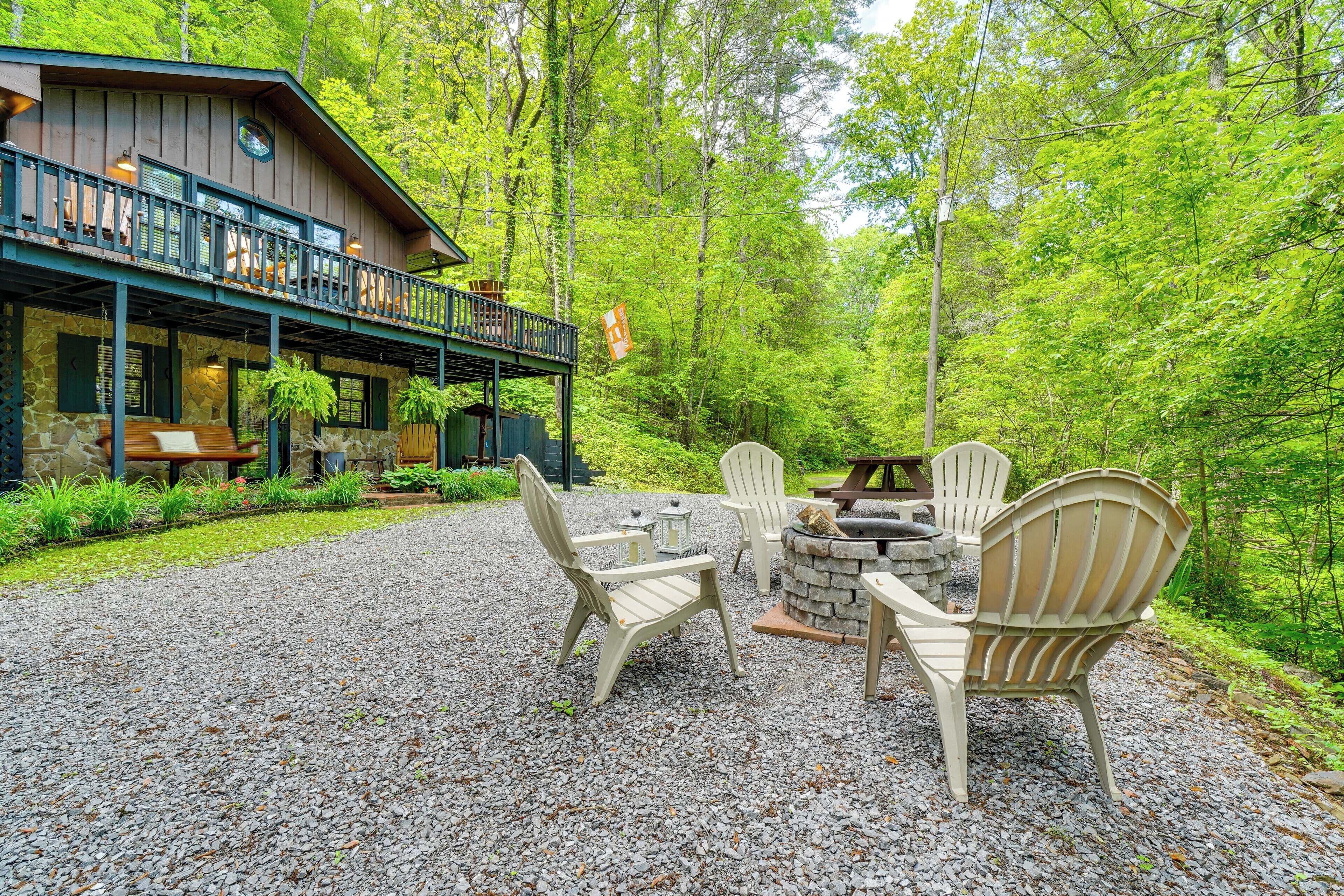 A cabin with a deck, outdoor seating, and a stone fireplace.