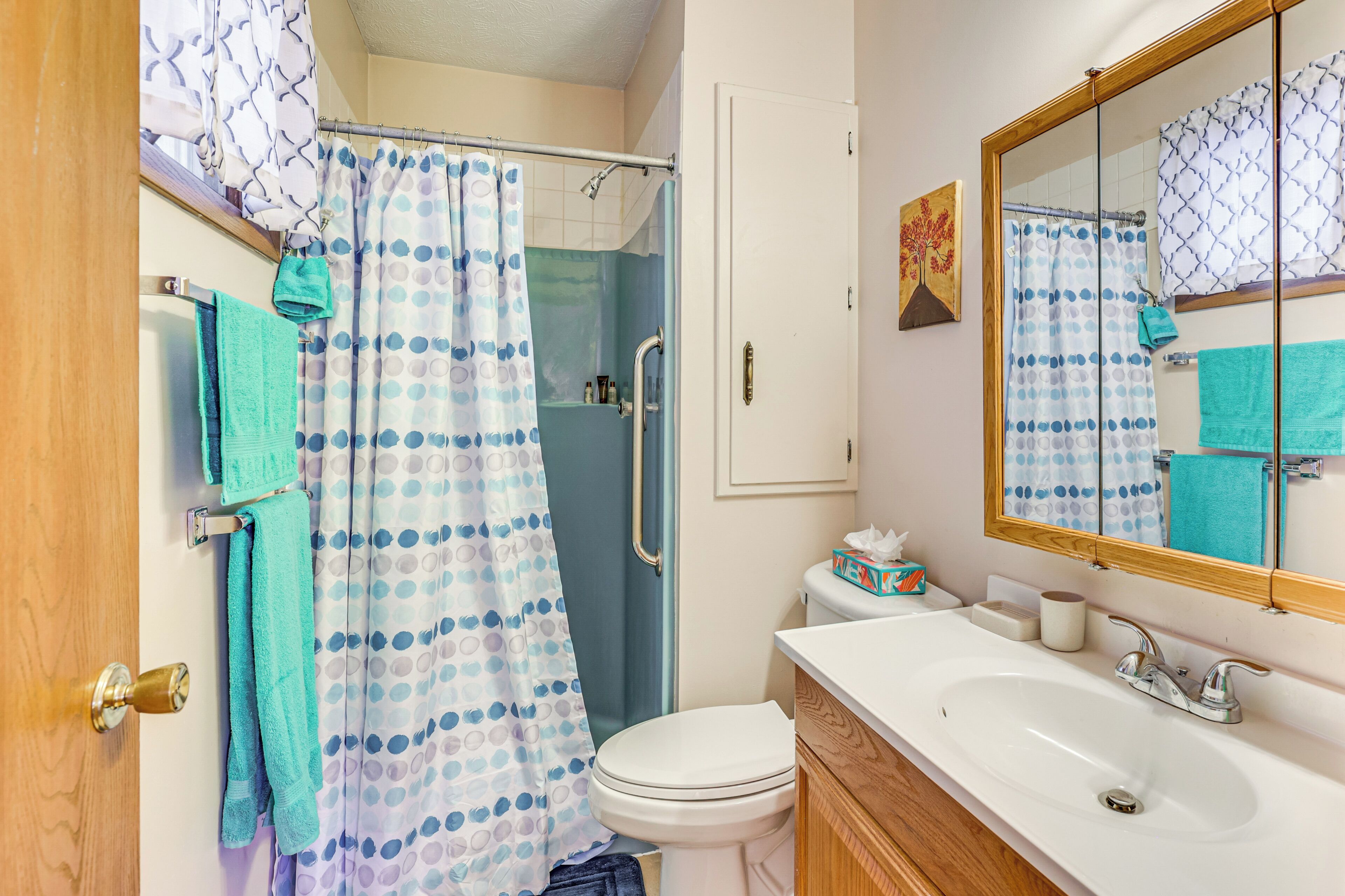 A bathroom with a shower, toilet, sink, and a mirror.
