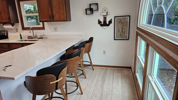 A modern kitchen with a large island, wooden bar stools, and a window with a view of the outdoors. - SHORT WALK TO BEACH, QUIET RESIDENTIAL NEIGHBORHOOD (Ocean City)