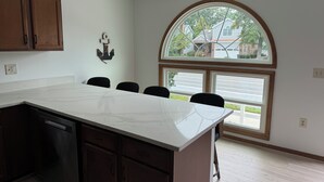 A kitchen with a marble countertop, wooden cabinets, and a large window with a view of the street. - SHORT WALK TO BEACH, QUIET RESIDENTIAL NEIGHBORHOOD (Ocean City)