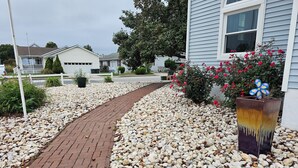 A pathway leading to a house with a gravel driveway and a flower pot with red flowers. - SHORT WALK TO BEACH, QUIET RESIDENTIAL NEIGHBORHOOD (Ocean City)