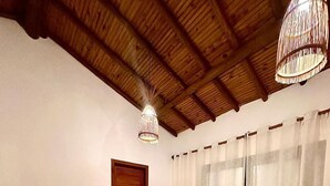 A room with a wooden ceiling, two chairs, a large rug, and a door. - Casa nobre Trancoso  (Porto Seguro)