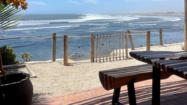 A beachside patio with a wooden table and bench, overlooking the ocean. - HOP MAR Surfea las Mejores Olas de Puemape (Puémape)