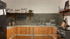 A kitchen with wooden cabinets, a built-in oven, and a hanging light fixture. - HOP MAR Surfea las Mejores Olas de Puemape (Puémape)