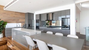 A modern kitchen with a central island, grey cabinets, and stainless steel appliances.