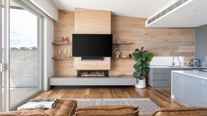 A modern living room with a fireplace, a flat-screen TV, and a large window.