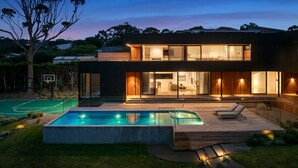 Een modern huis met twee verdiepingen, een zwembad en een terras.