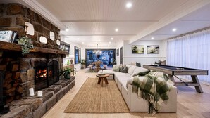 A cozy living room with a stone fireplace, a pool table, and a comfortable sofa. - Bella s Cottage Spa Sauna Large Groups (Yarra Glen)
