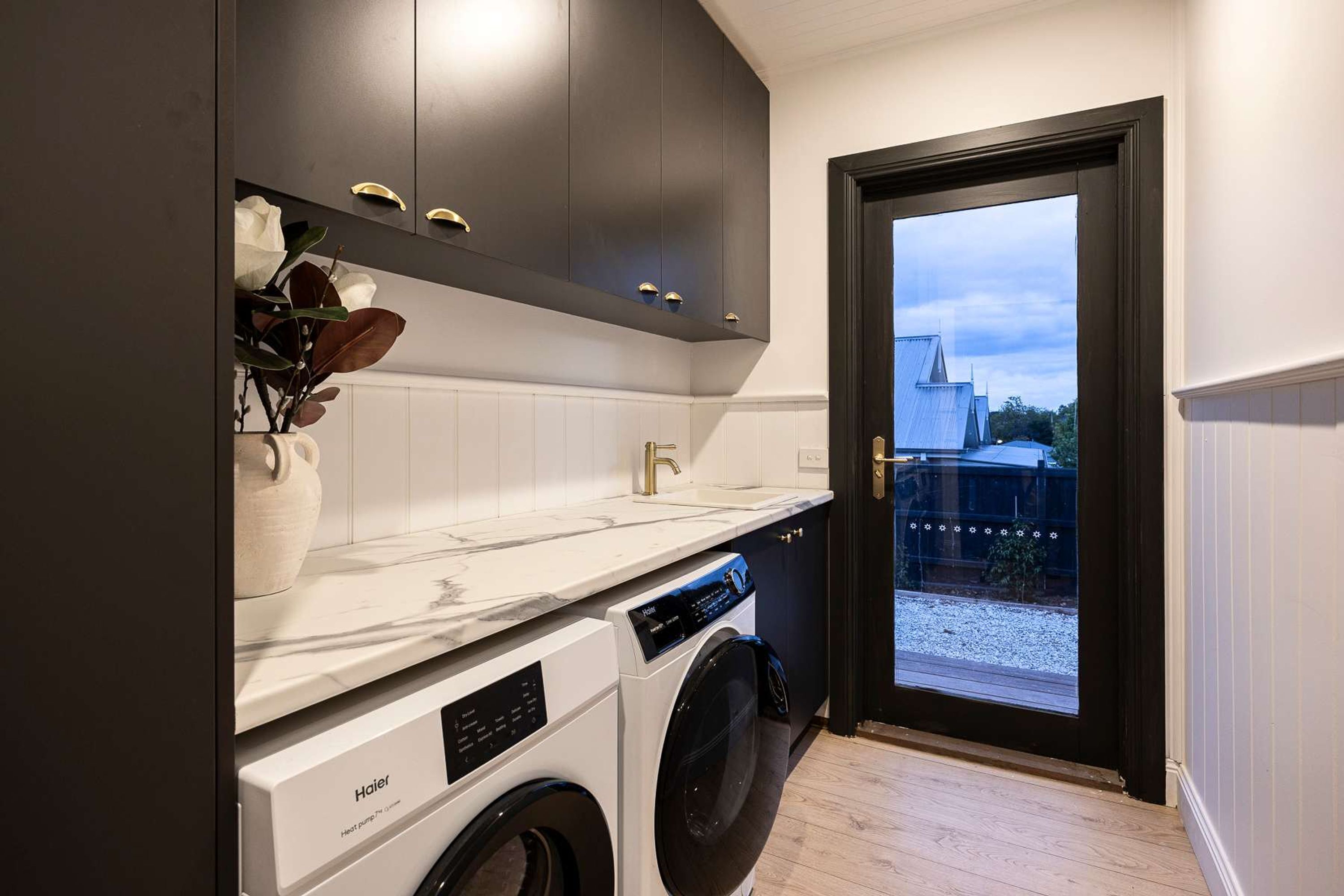 A modern kitchen with dark cabinets, a white countertop, and a built-in washing machine.