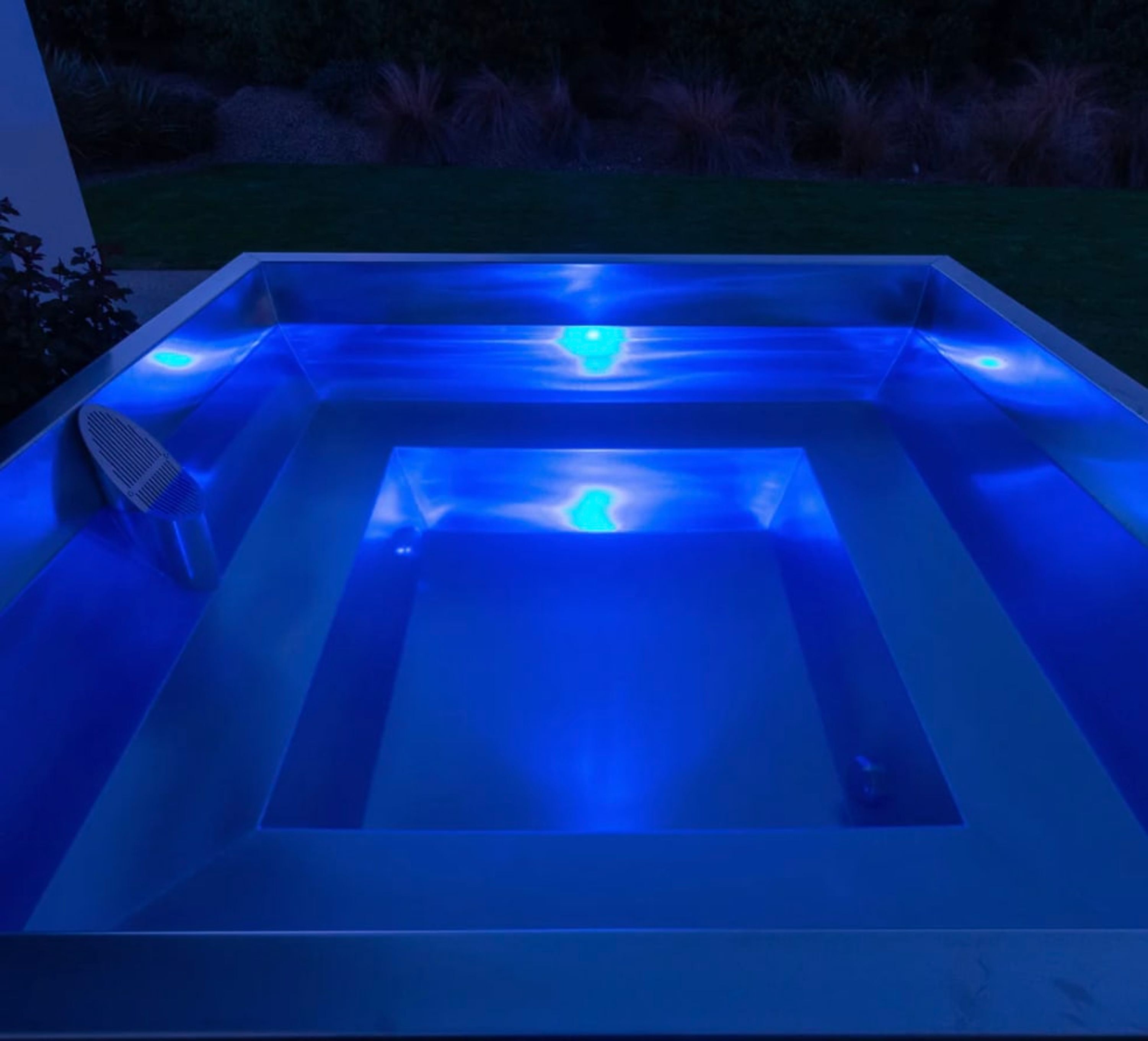 A rectangular hot tub with a blue light.