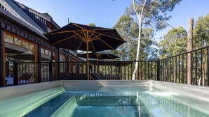 A swimming pool with a glass bottom, surrounded by a wooden deck and a metal railing. - Onyx Retreat Healesville Luxury Lodge x Hot Tub (Healesville)