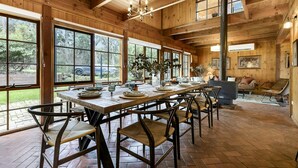 A wooden interior with a long dining table, chairs, and large windows. - Onyx Retreat Healesville Luxury Lodge x Hot Tub (Healesville)