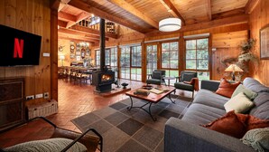 A cozy log cabin interior with a fireplace, comfortable seating, and large windows. - Onyx Retreat Healesville Luxury Lodge x Hot Tub (Healesville)