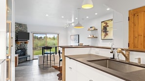 Une cuisine moderne dotée d’un grand îlot central, d’une cuisinière intégrée et de luminaires suspendus.