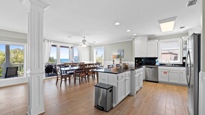 A spacious kitchen with white cabinetry, a central island, and a dining area with wooden chairs. - Tranquility on beautiful St. George Island (St. George Island)