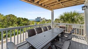 A covered outdoor deck with a dining table and chairs, overlooking a scenic view of a beach and ocean. - Tranquility on beautiful St. George Island (St. George Island)