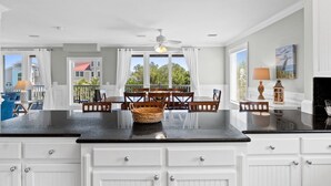 A kitchen with white cabinetry, a black countertop, and a dining area with wooden chairs and a table. - Tranquility on beautiful St. George Island (St. George Island)