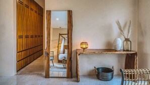 A hallway with wooden lockers, a rustic wooden console table with a lamp, and a wicker chair. - 3BR Deluxe PH w Private Pool + Rooftop (Tulum)