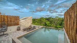 A pool area with lounge chairs, a stone wall, and bamboo fencing. - 3BR Deluxe PH w Private Pool + Rooftop (Tulum)