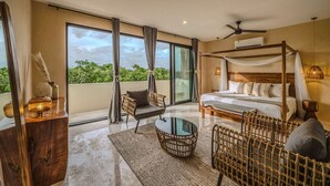 A spacious bedroom with a large bed, a canopy, a sitting area with a table, and a balcony with a view of greenery. - 3BR Deluxe PH w Private Pool + Rooftop (Tulum)