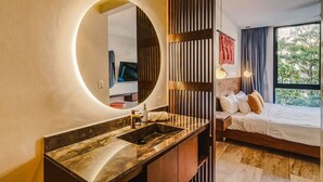 Een moderne badkamer met een ronde spiegel, een wastafel en een toilet.