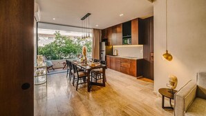 Een moderne keuken met houten kastjes, een inbouwoven en een eethoek met een glazen tafel en stoelen.
