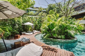 A pool area with a wooden deck, lounge chairs, and a small island with tropical plants. - Divine 3BR PH Private Jacuzzi | Pools | Yoga (Tulum)