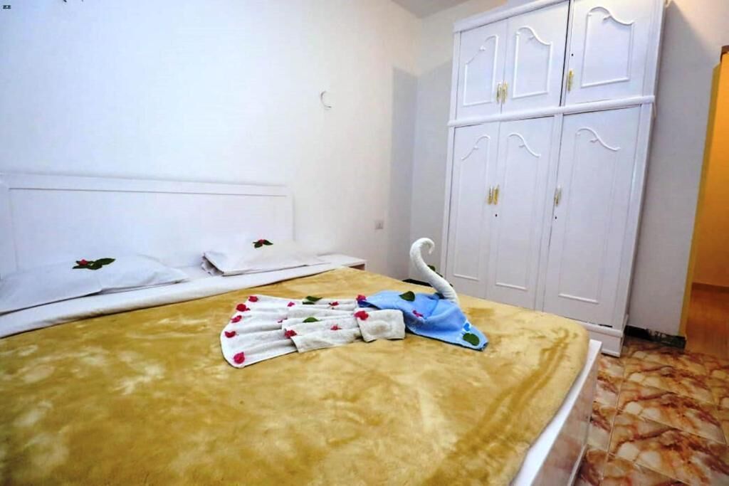 Une chambre d’hôtel avec un lit, une armoire blanche et un porte-serviettes en forme de cygne.