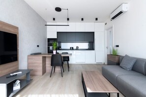 Un salon moderne comprenant un canapé, une table basse, un téléviseur et un coin repas avec des chaises.