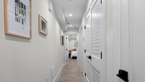 A hallway with white walls, wooden flooring, and doors with black handles.