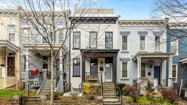 A row of townhouses with stone steps leading to the front door, a small porch, and a mailbox.