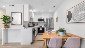 A modern kitchen with white cabinetry, stainless steel appliances, and a central island.