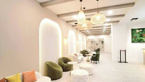 A modern interior with a white sofa, green armchairs, and round ottomans. - MoonShine Inn (Taoyuan City)