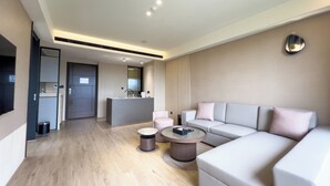 A modern living room with a sofa, coffee table, and a kitchen area in the background. - MoonShine Inn (Taoyuan City)