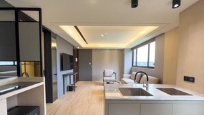 A modern kitchen with a central island, built-in appliances, and a seating area with a sofa and chair. - MoonShine Inn (Taoyuan City)