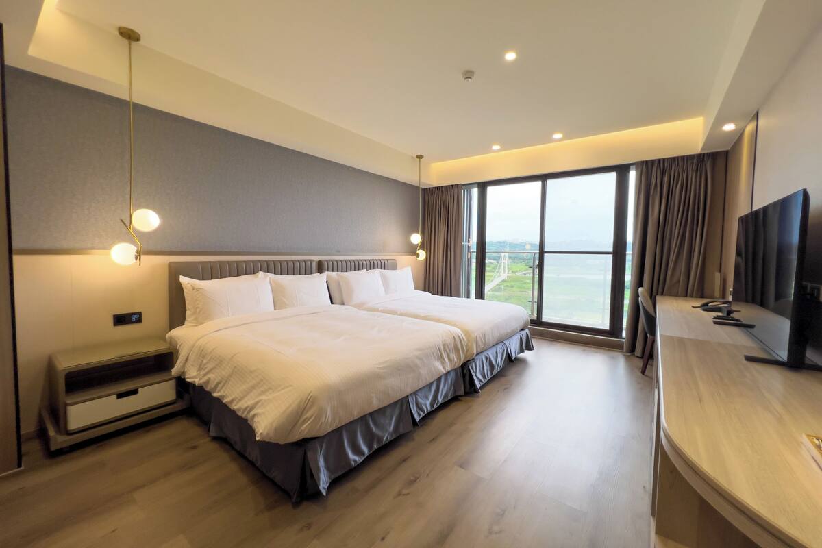 Une chambre d’hôtel moderne avec un grand lit, une télévision et une vue sur un pont.