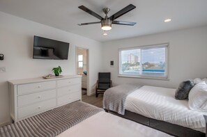 A bedroom with a bed, a TV, a ceiling fan, a window with blinds, and a white dresser. - Right on the Famous Mission Beach Boardwalk - Sleeps up to 10 - Best location in Mission Beach (San Diego)