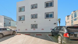 A modern building with multiple windows and a parking lot with cars. - Right on the Famous Mission Beach Boardwalk - Sleeps up to 10 - Best location in Mission Beach (San Diego)