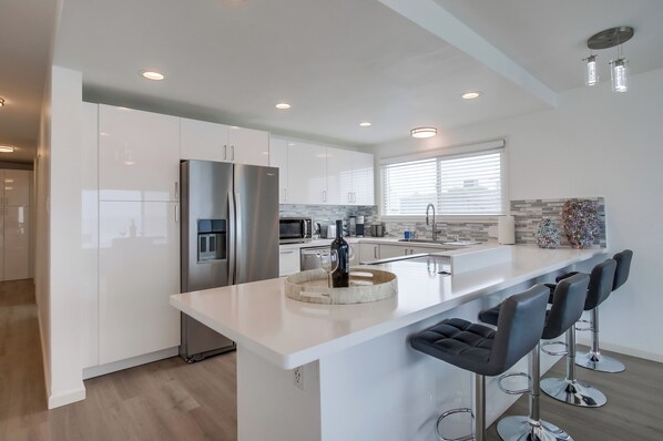 A modern kitchen with a central island, stainless steel appliances, and bar stools.