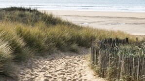 A sandy beach path leading to the ocean, with grass and a wooden fence. - Natural lagoon and relaxation for 6 (Saint-Vincent-sur-Jard)