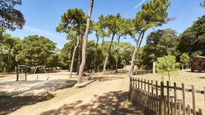 A playground with swings and a slide, surrounded by trees and a wooden fence. - Natural lagoon and relaxation for 6 (Saint-Vincent-sur-Jard)