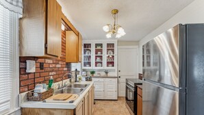 A kitchen with wooden cabinets, a stainless steel refrigerator, and a brick backsplash. - 2BR Near Niagara Falls Parking + WiFi (Niagara Falls)