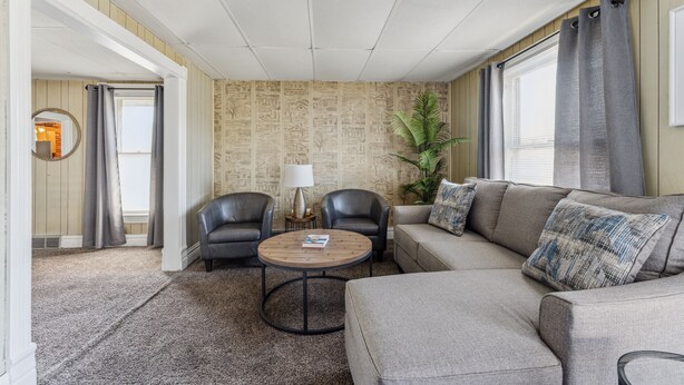 A living room with a sectional sofa, two armchairs, a round coffee table, and a lamp. - 2BR Near Niagara Falls Parking + WiFi (Niagara Falls)