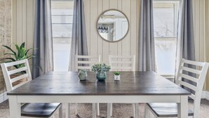 A dining area with a dark wooden table, white chairs, and a mirror on the wall. - 2BR Near Niagara Falls Parking + WiFi (Niagara Falls)