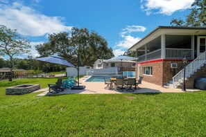 A backyard with a pool, outdoor seating, and a covered patio area. - Beautiful Lake View Retreat Drivable To Theme Parks 3 Bedroom Home (Haines City)