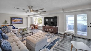 A modern living room with a sofa, ottoman, coffee table, and a TV. - Beautiful Lake View Retreat Drivable To Theme Parks 3 Bedroom Home (Haines City)